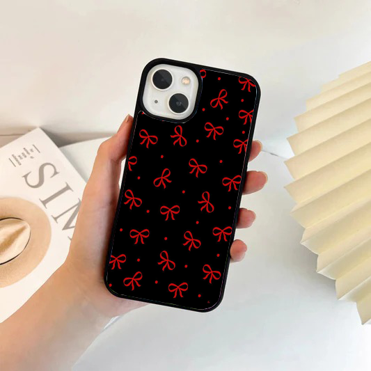 Black phone case with a repeating pattern of simple bright red bows and small red polka dots.